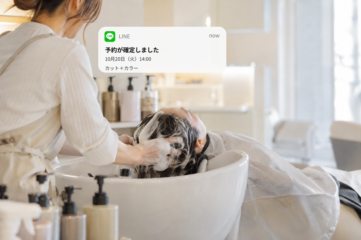 美容院でシャンプー施術をする美容師と、写真右上のLINE予約通知のイメージ。予約が確定しました。10月20日（火）14:00、カット＋カラー。